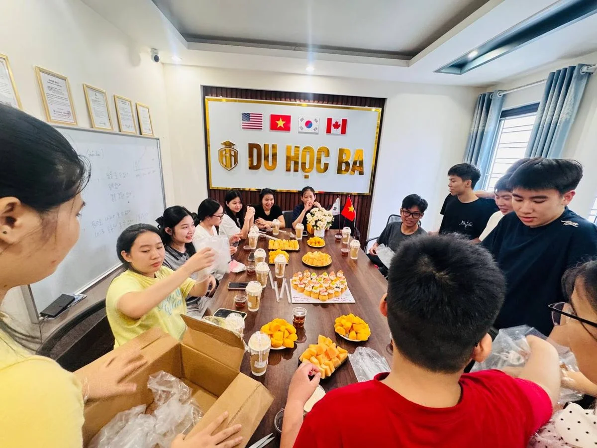 Học viên nam và nữ lớp tiếng Hàn Du Học BA quây quanh bàn tiệc 20/10, bóc bánh và trà sữa