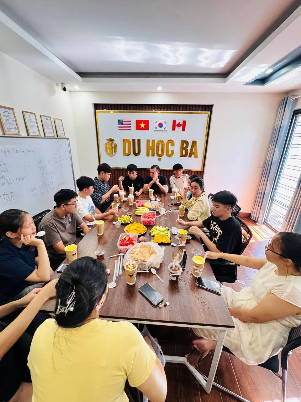 Thầy cô và học viên Du Học BA ngồi quanh bàn tiệc hoa quả mừng ngày Phụ nữ Việt Nam 20/10